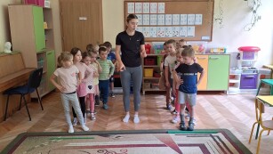 Dzieci ustawione w dwóch rzędach słuchają instrukcji wykonywania ćwiczeń