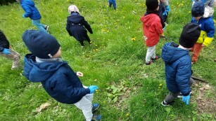 Dzieci szukają śmieci na trawiastym terenie.